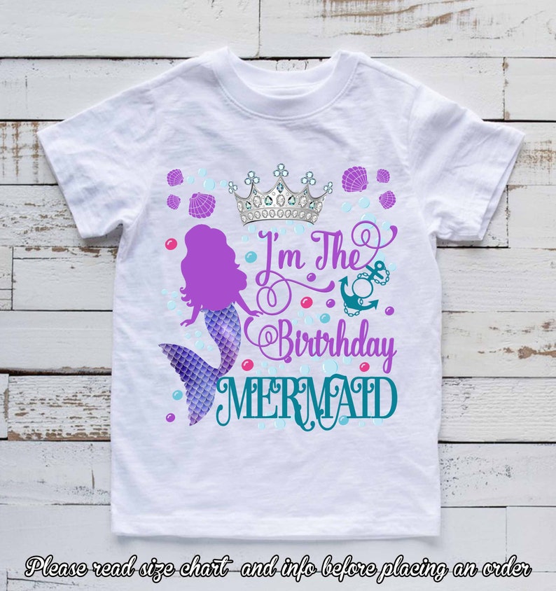 K&ouml;nnte beinhalten: Wei&szlig;es T-Shirt mit einem Meerjungfrau-Design. Das Design zeigt eine lila Meerjungfrau, eine silberne Krone und den Text "I'm The Birthday Mermaid" in Lila und T&uuml;rkis. Blasen und Muscheln erg&auml;nzen das Design.