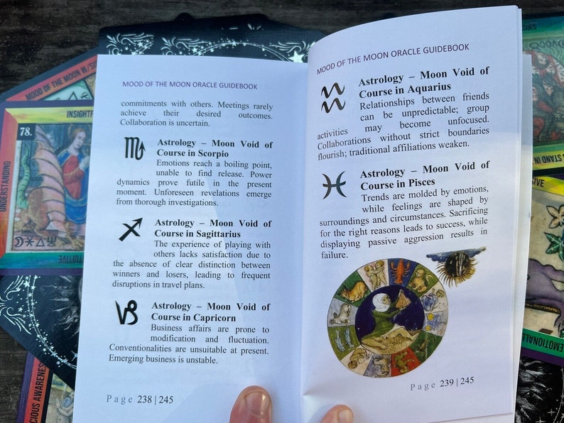 Może przedstawiać: Książka z czarno-białą ilustracją koła zodiaku. Książka jest otwarta na stronie z tekstem o pustce kursu Księżyca w każdym znaku zodiaku. Tekst zawiera astrologiczny symbol każdego znaku. Książka nosi tytuł "Mood of the Moon Oracle Guidebook".
