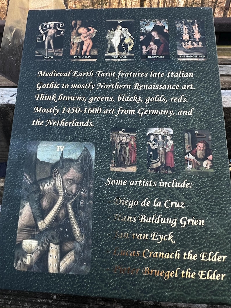 May include: A dark green tarot card featuring illustrations of tarot cards and text. The text describes the Medieval Earth Tarot, its art style, and the artists involved. The card's color palette includes browns, greens, blacks, golds, and reds.