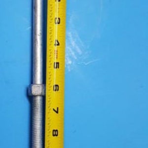 May include: A silver metal eye bolt with a threaded shaft and a ring at the top. The bolt is 11 inches long and the ring is approximately 1 inch in diameter.