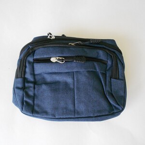 May include: A dark blue fanny pack with black zippers and a silver zipper pull.