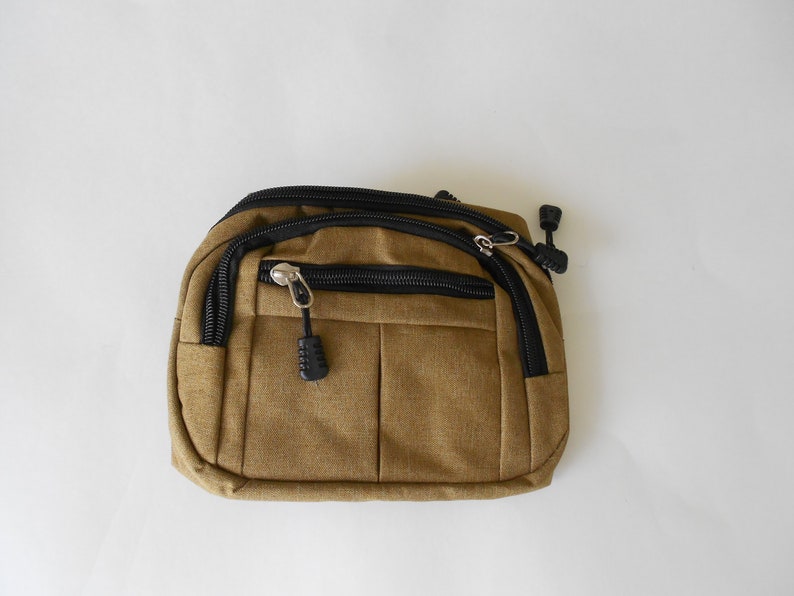 May include: A small brown canvas fanny pack with black zipper accents and a black zipper pull.