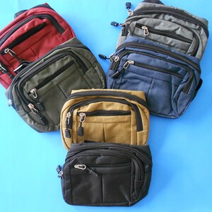 May include: Six fanny packs in different colors, including red, green, brown, black, blue, and gray. The fanny packs have multiple zippered compartments and are made of a durable fabric.