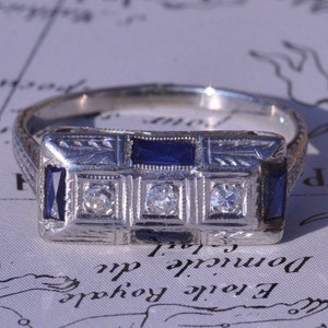 Antiguo anillo Art Deco de tres diamantes y zafiro en oro blanco de 18 quilates