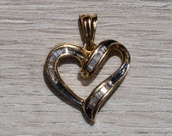 May include: A gold heart-shaped pendant with a diamond-like design. The pendant is about the size of a dime.
