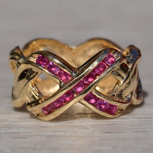 以下が含まれることがあります： 十字架のデザインとピンクの宝石が付いた金の指輪