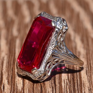 May include: A vintage ring featuring a large, rectangular, red gemstone set in a filigree design.