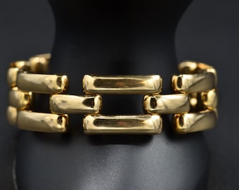 May include: A gold-toned bracelet with a linked chain design. The bracelet is made of multiple rectangular links that are connected to each other.