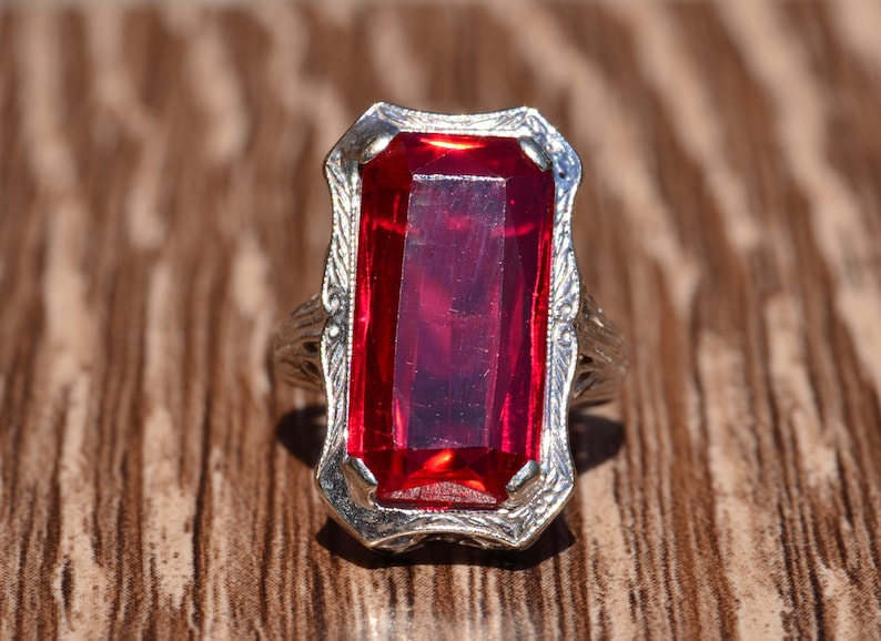 May include: A silver ring with a large, rectangular, red gemstone.