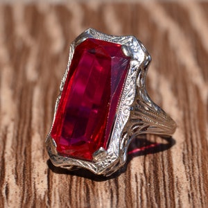May include: A vintage ring featuring a large, rectangular, red gemstone set in a filigree silver band.