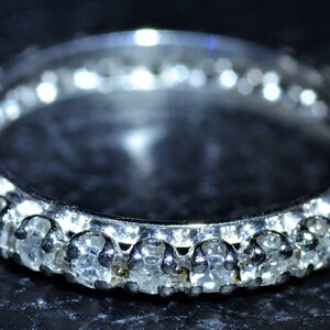May include: A silver band ring with a row of small, clear gemstones.