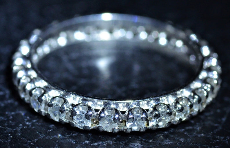 May include: A silver band ring with a row of small, clear gemstones.
