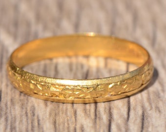 May include: A simple gold band ring with a delicate, engraved design. The ring is smooth and shiny, with a classic look.
