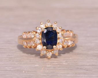 May include: A gold ring with a large oval blue sapphire surrounded by a halo of smaller diamonds.