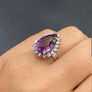 May include: A pear-shaped amethyst ring with a halo of small diamonds set in silver.