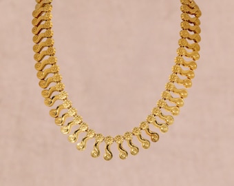 Könnte beinhalten: Eine goldfarbene Halskette mit einer Reihe von sich wiederholenden S-förmigen Gliedern. Jedes Glied ist durch ein kleines, kreisförmiges Element mit Blumenmuster verbunden, was ein durchgehendes, geschwungenes Design ergibt.