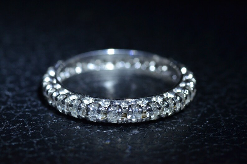 May include: A silver band ring with a row of small, clear gemstones.