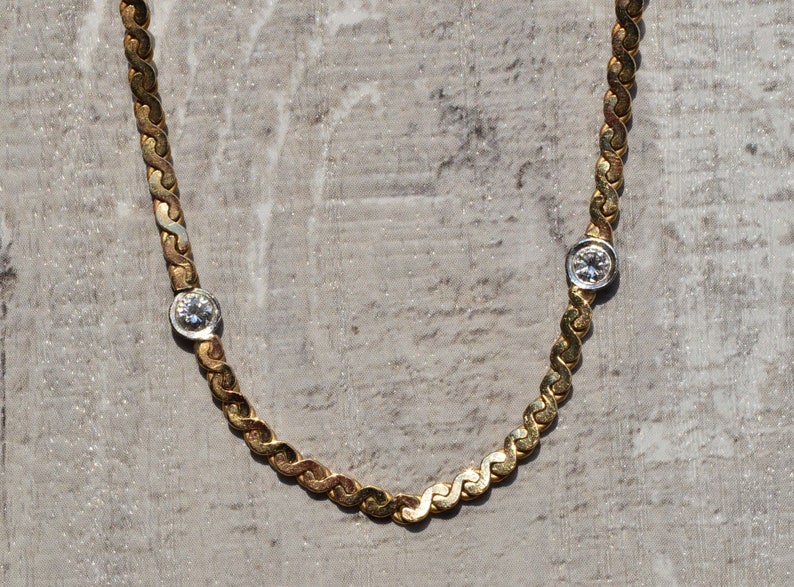 May include: A gold chain necklace with two small round diamonds.