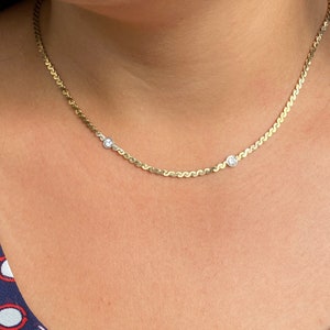 May include: A gold chain necklace with two small round clear stones.