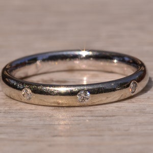 May include: A simple silver band ring with three small diamonds set into the band.