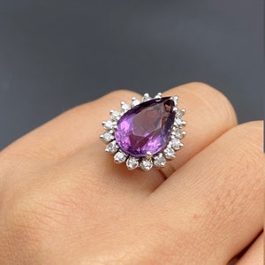 May include: A pear-shaped amethyst ring with a halo of smaller diamonds set in silver.