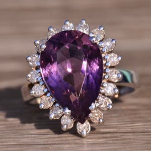 May include: A pear-shaped amethyst ring with a halo of smaller diamonds set in silver.