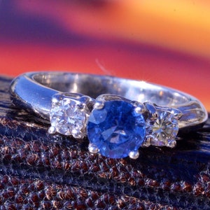 Anillo de compromiso firmado de zafiro azul aciano y diamante de tres piedras