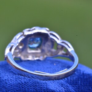 K&ouml;nnte beinhalten: Ein silberner Ring mit einem blauen Edelstein, der in einem filigranen Design gefasst ist.