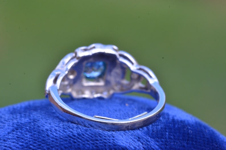 K&ouml;nnte beinhalten: Ein silberner Ring mit einem blauen Edelstein, der in einem filigranen Design gefasst ist.