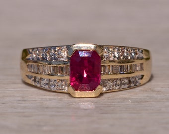 May include: A gold ring with a large, red, rectangular ruby gemstone surrounded by smaller, clear, rectangular gemstones.