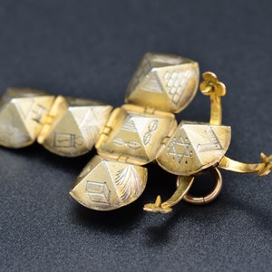 May include: A gold-colored pendant with a hinged, multi-sided design. Each side features a different engraved symbol, including a Star of David, a pyramid, and a menorah.