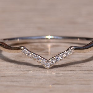 Könnte beinhalten: Ein zarter Silberring mit einem V-förmigen Band, das mit kleinen Diamanten besetzt ist.
