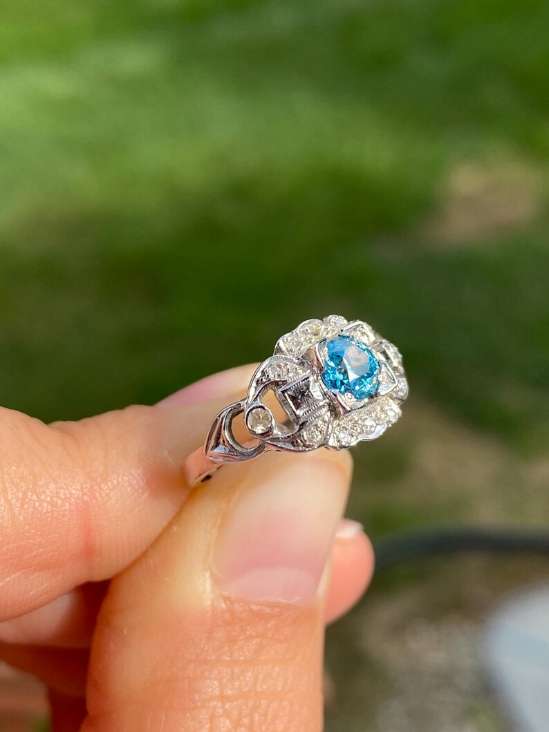 K&ouml;nnte beinhalten: Ein silberner Ring mit einem blauen Edelstein, der von kleineren wei&szlig;en Edelsteinen umgeben ist.