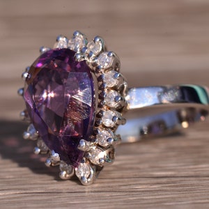 May include: A pear-shaped amethyst ring with a silver band and a halo of small diamonds.