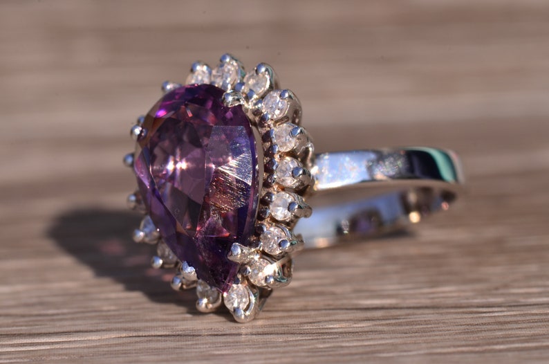 May include: A pear-shaped amethyst ring with a silver band and a halo of small diamonds.