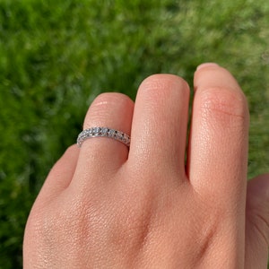 May include: A silver band ring with a row of small, clear gemstones.