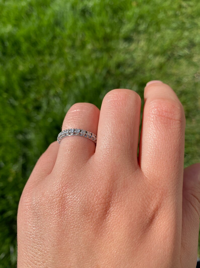 May include: A silver band ring with a row of small, clear gemstones.