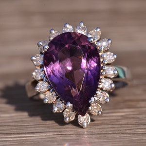 May include: A pear-shaped amethyst ring with a halo of smaller diamonds set in silver.