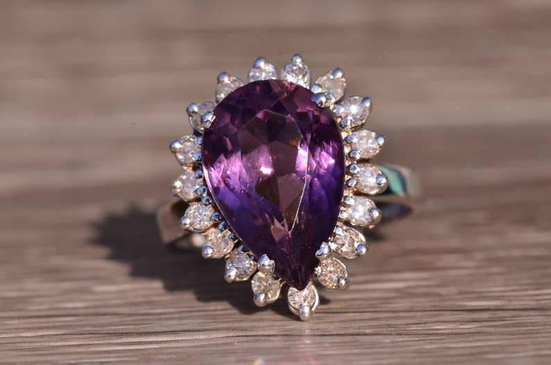 May include: A pear-shaped amethyst ring with a halo of smaller diamonds set in silver.
