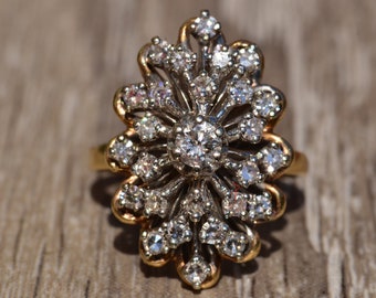 May include: A gold ring with a large, sparkling diamond center stone surrounded by smaller diamonds. The ring is set in a floral design with delicate, intricate details.