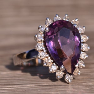 May include: A pear-shaped amethyst ring with a halo of small diamonds set in silver.