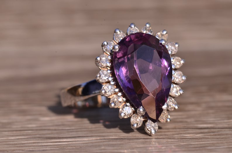 May include: A pear-shaped amethyst ring with a halo of small diamonds set in silver.