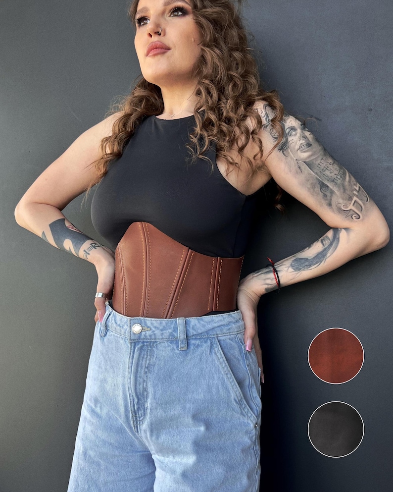 May include: A brown leather corset with vertical stitching. The corset is worn over a black top and paired with light blue denim jeans. Two color swatches, brown and black, are shown on the right side of the image.