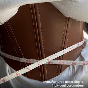 May include: A brown corset with vertical stitching and a measuring tape wrapped around it. The tape shows measurements from 29 to 37 inches. Text at the bottom reads "Waist reduction from 2 to 5 inches!"