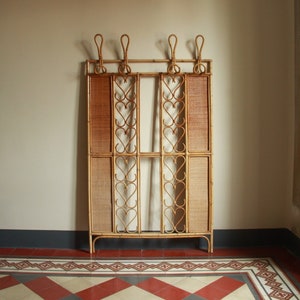 Könnte beinhalten: Ein brauner Korb-Raumteiler mit einem dekorativen Metalldesign. Der Teiler hat vier Paneele und steht auf einem gefliesten Boden.