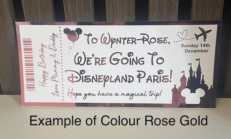 K&ouml;nnte beinhalten: Eine ros&eacute;goldene Karte im Ticketstil k&uuml;ndigt eine Reise nach Disneyland Paris an. Die Karte enth&auml;lt den Text "Happy Birthday", "Love Mummy & Daddy" und "We're Going To Disneyland Paris!" mit einer Mickey Mouse Silhouette.