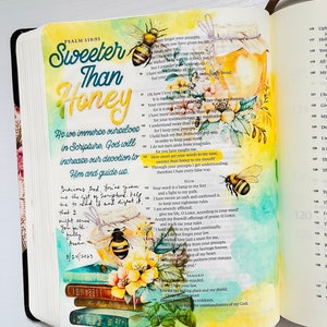 Op de afbeelding: Een pagina uit de Bijbel met de woorden "Sweeter Than Honey" in kleurrijke letters. De pagina is versierd met een aquarel van een pot honing, bijen en bloemen. De tekst op de pagina is Psalm 119:93, die luidt: "Hoe zoet zijn uw woorden voor mijn smaak, zoeter dan honing voor mijn mond!"