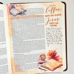 May include: A Bible page with handwritten notes and a watercolor illustration of a coffee cup, a vase of flowers, and a book. The text on the page reads "Coffee keeps me warm, Jesus keeps me strong." The handwritten notes say "God's Word promises that if we fully rely on Him as our portion, we will never get spiritually hungry or thirsty. If you feel like you are either of those, start your day in His Word and allow Him to fill you up."