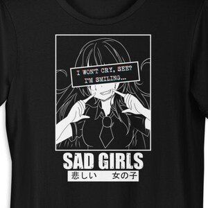 Könnte beinhalten: Schwarzes T-Shirt mit einer weißen Grafik eines Anime-Mädchens mit dem Text "I won't cry, see? I'm smiling..." und "SAD GIRLS 悲しい 女の子" unter dem Bild.