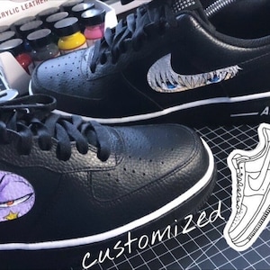 Könnte beinhalten: Paar schwarze Ledersneaker mit weißen Sohlen und Schnürsenkeln. Der Nike-Swoosh ist mit einem lila-weißen Anime-Design versehen. Das Wort "customized" ist auf der Oberfläche geschrieben.